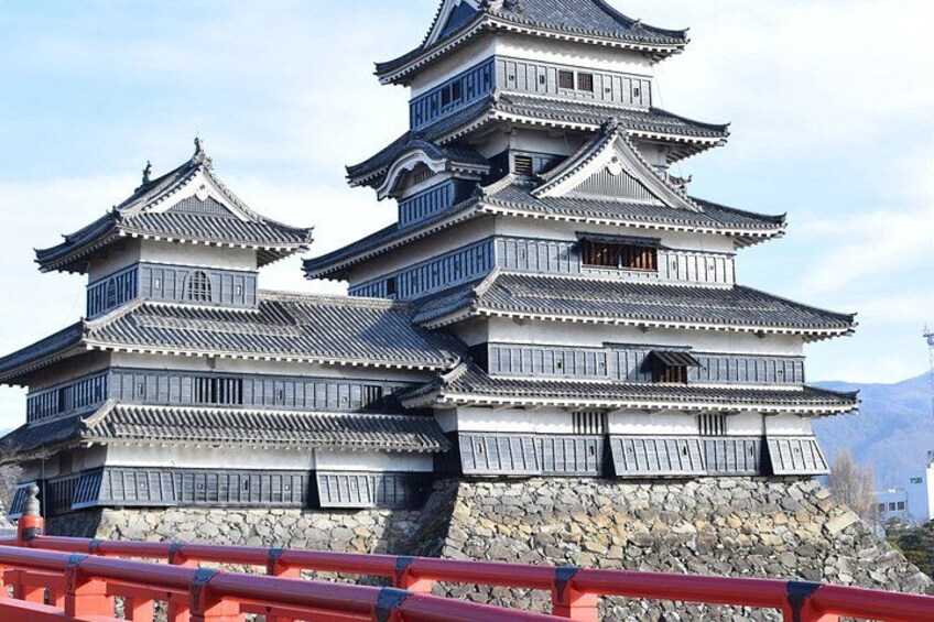 Un castillo japonés tradicional con varios niveles y base de piedra, con vista a un cuerpo de agua. 2