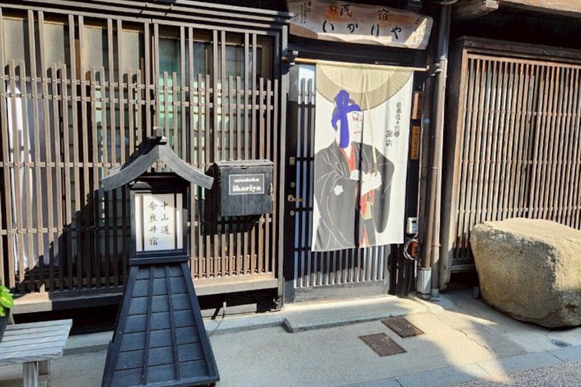 A traditional Japanese building with a wooden fence, a stone lantern, and a sign with Japanese characters. 4