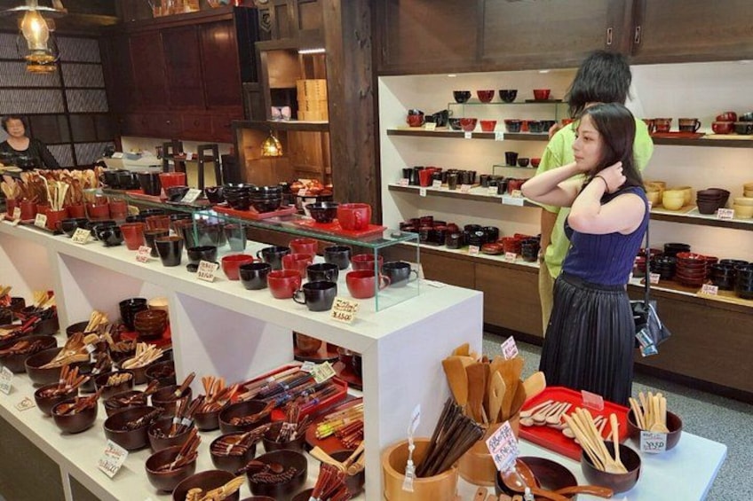 A store with shelves of red and black cups and bowls, and a person browsing. 5