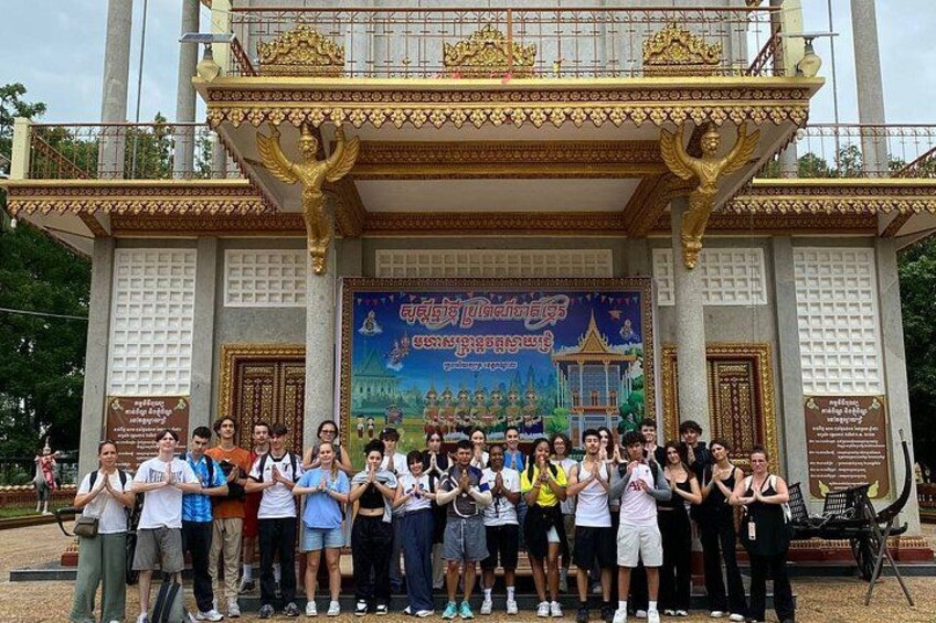 Un grupo de personas posando frente a un templo con un gran mural y detalles dorados. 3