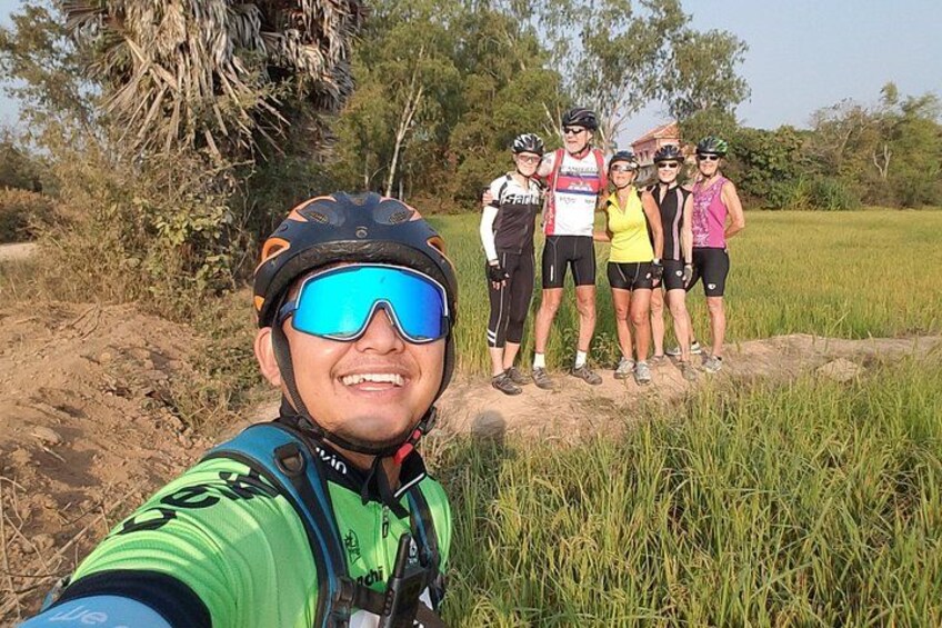 Un grupo de personas caminando por un sendero de tierra en una zona con hierba, con árboles al fondo. 4