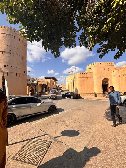 A historic fort with a round tower, a paved street, and a person walking. 3