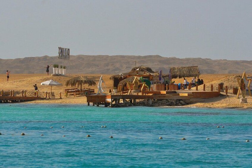 A beach with a wooden pier, a thatched-roof structure, and a desert landscape in the background. 4