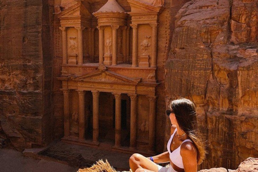 A person sitting in front of a large rock structure with columns. 2