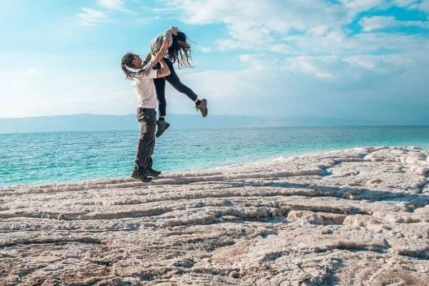 Due persone su una spiaggia rocciosa con il mare sullo sfondo. 2