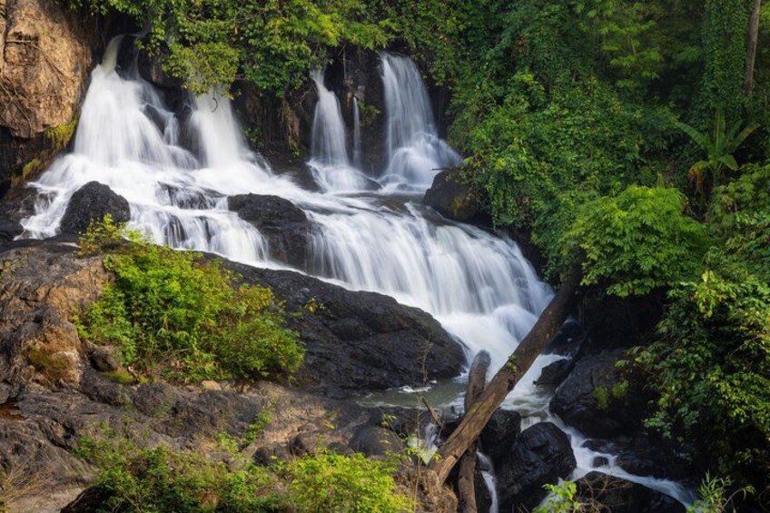 A waterfall cascading over rocks surrounded by lush greenery. 5