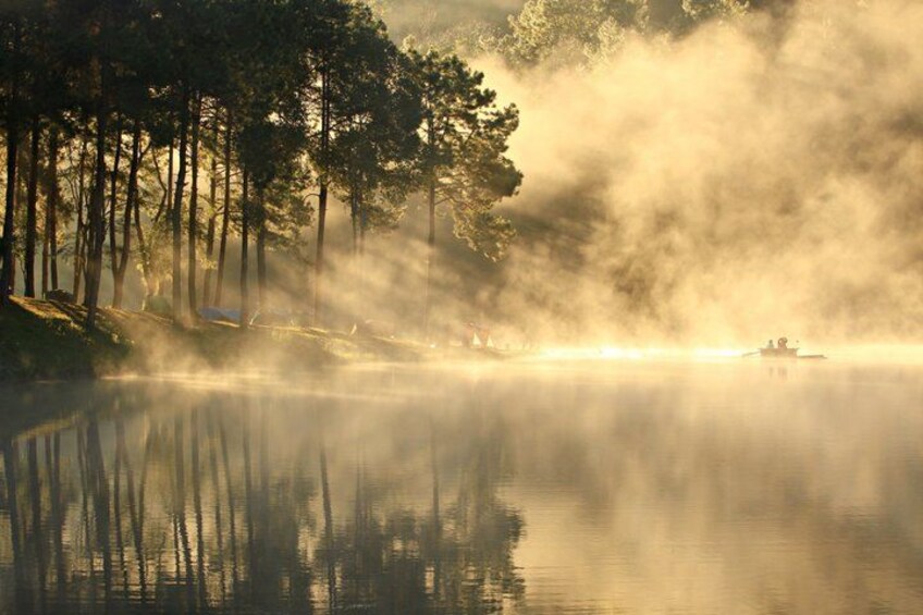 A misty lake with reflections of trees and a boat. 1