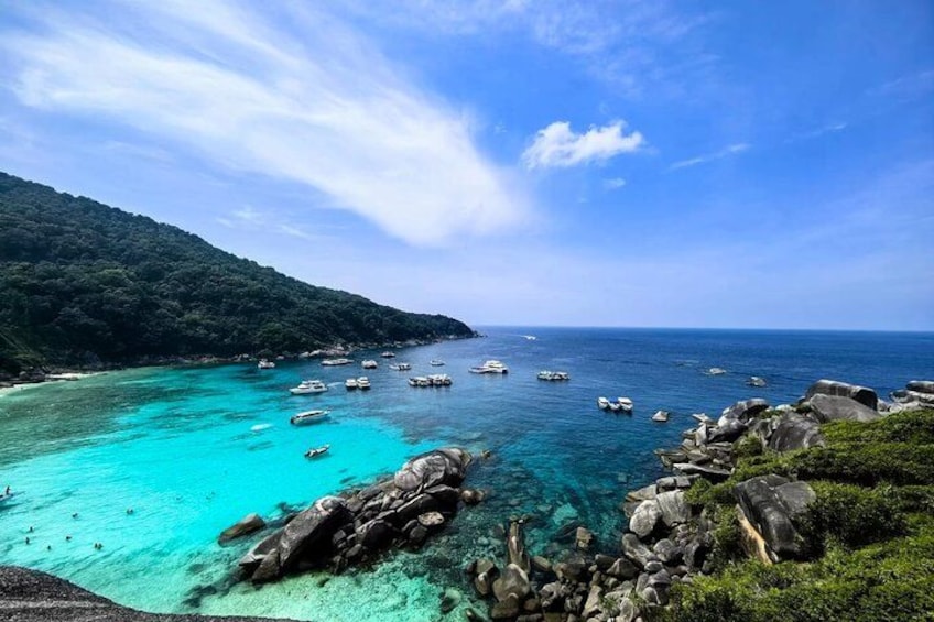 Un paisaje costero con aguas turquesas cristalinas, afloramientos rocosos y barcos fondeados cerca de la orilla. 3