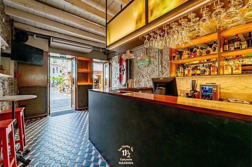 A bar with a counter, stools, and shelves of bottles. 5