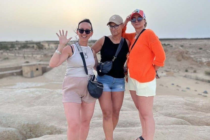 Tres personas en terreno rocoso, con un paisaje desértico al fondo. 2