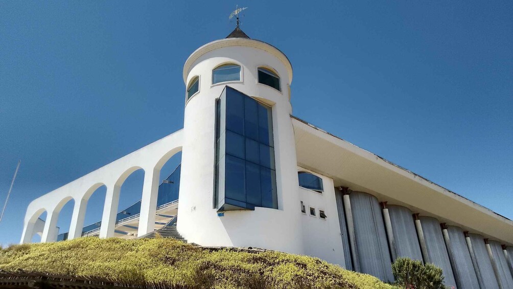 A modern white church with a central tower, arched windows, and a clear blue sky. 1