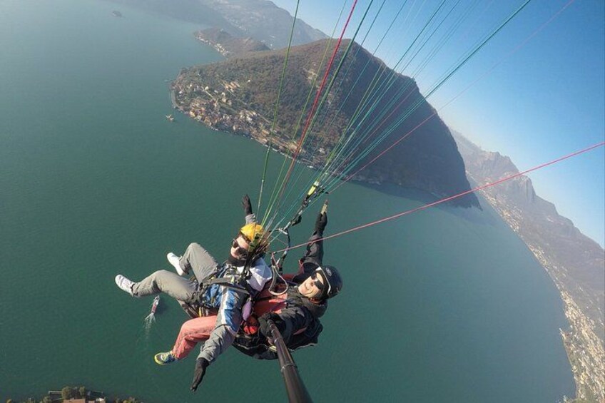 Dos personas hacen parapente sobre una masa de agua, con un paisaje montañoso al fondo. 4