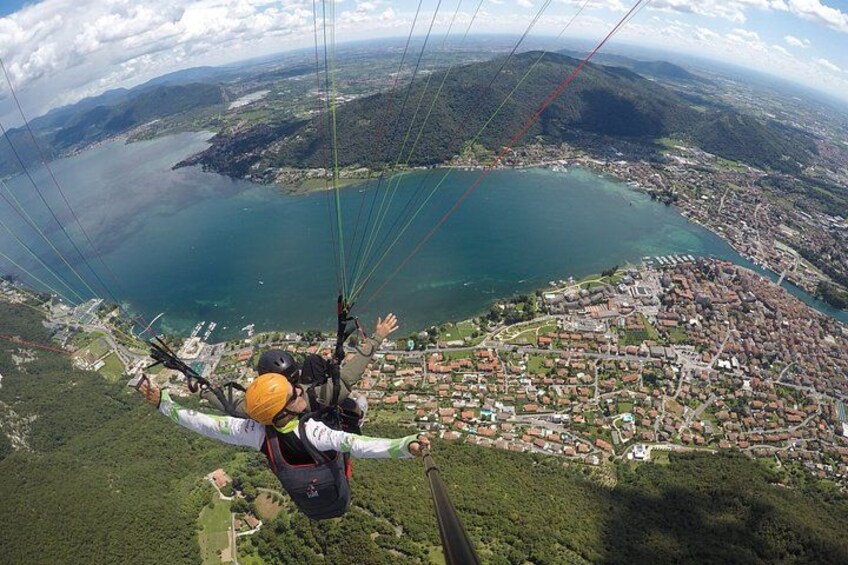 Escena de parapente con una persona en arnés y casco, un paisaje montañoso, un lago y un pueblo abajo. 5