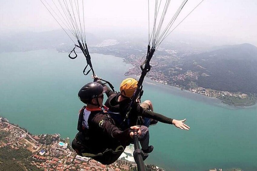 Una persona practicando parapente sobre una masa de agua, con un paisaje debajo. 3