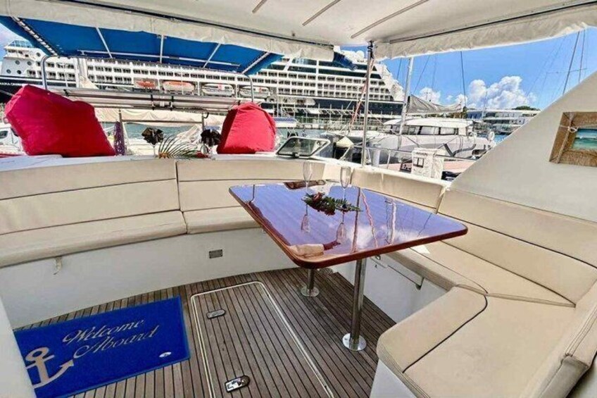 A yacht deck with a table, cushions, and a welcome sign. 5