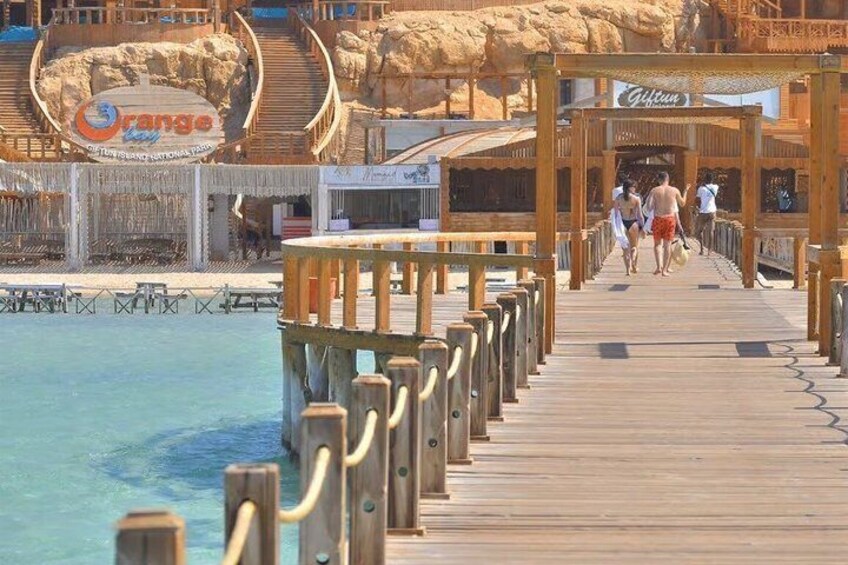 Un molo di legno che conduce a una spiaggia, con un cartello per il ristorante 'Orange' e 'Gulf'. 1