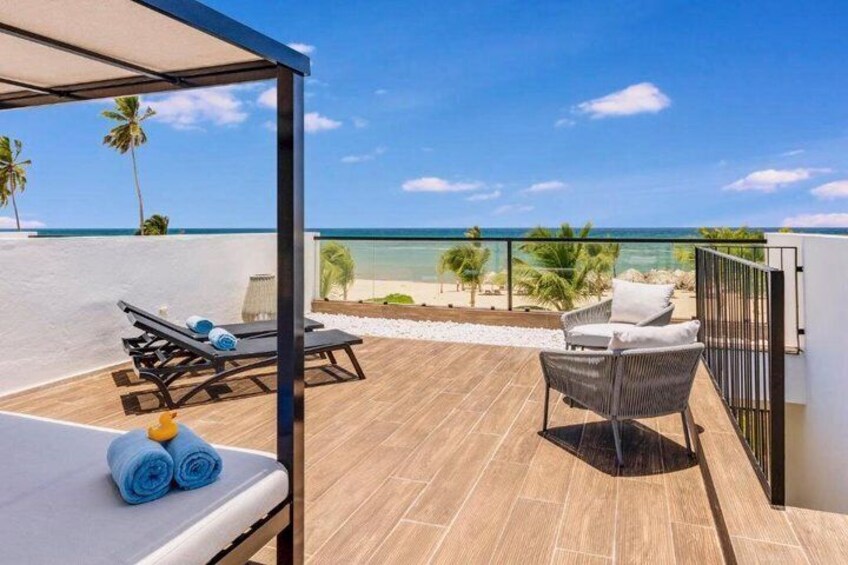 Terraza de madera con sillones de descanso y vista a la playa. 5