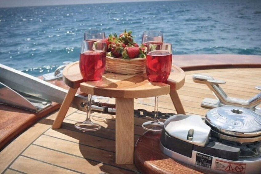 Una mesa de madera con bebidas y fruta en la cubierta de un barco. 3