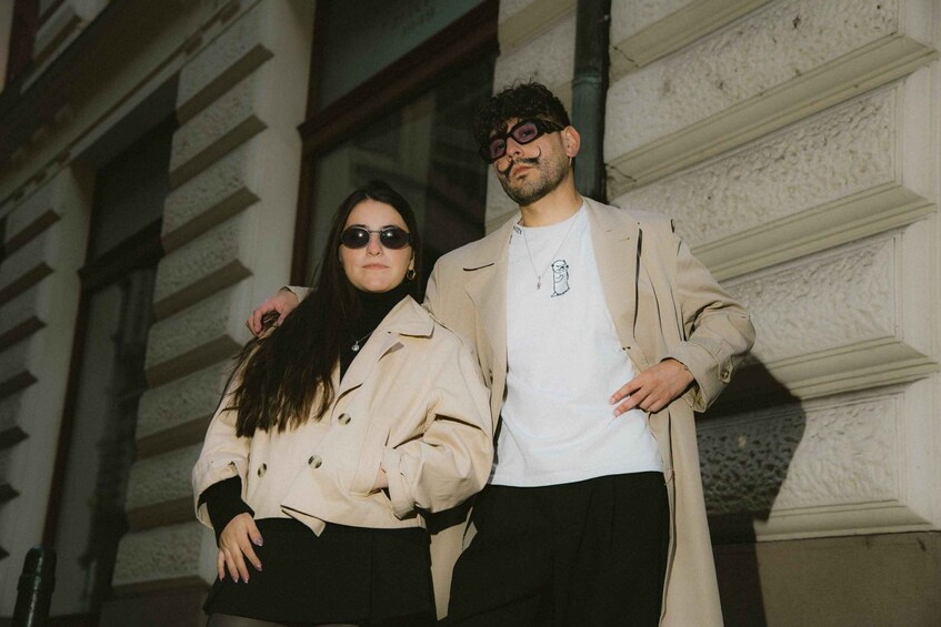Two people standing in front of a building with a stone facade and large windows. 1