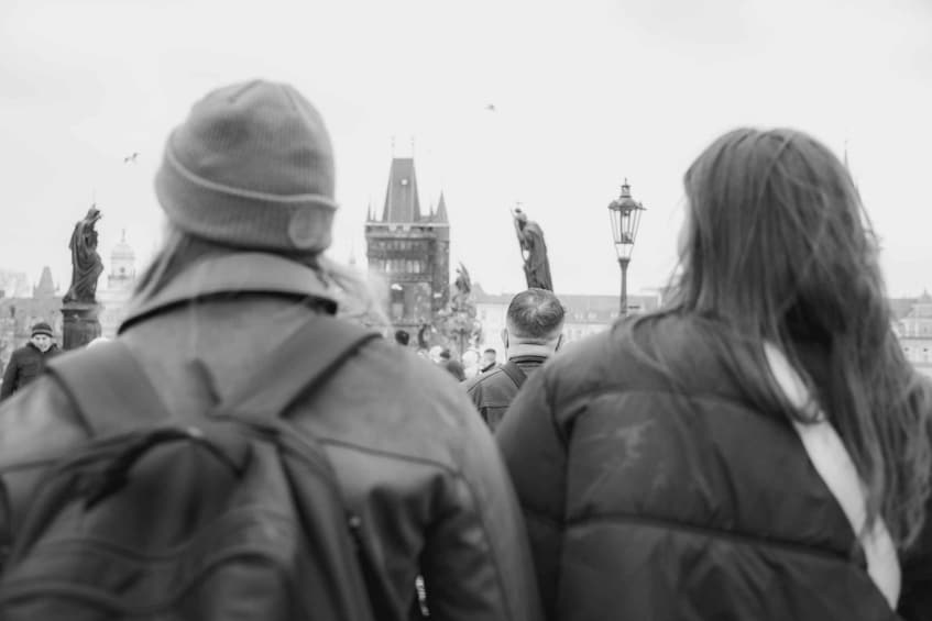 Two people walking away from the camera, a statue, and a tower in the background. 4