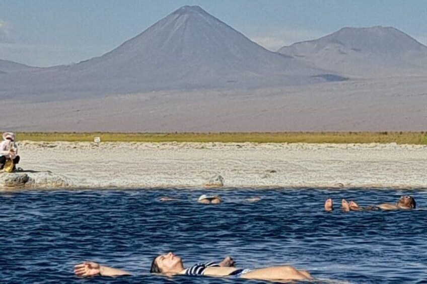 Menschen schwimmen in einem Gewässer, im Hintergrund Berge. 1