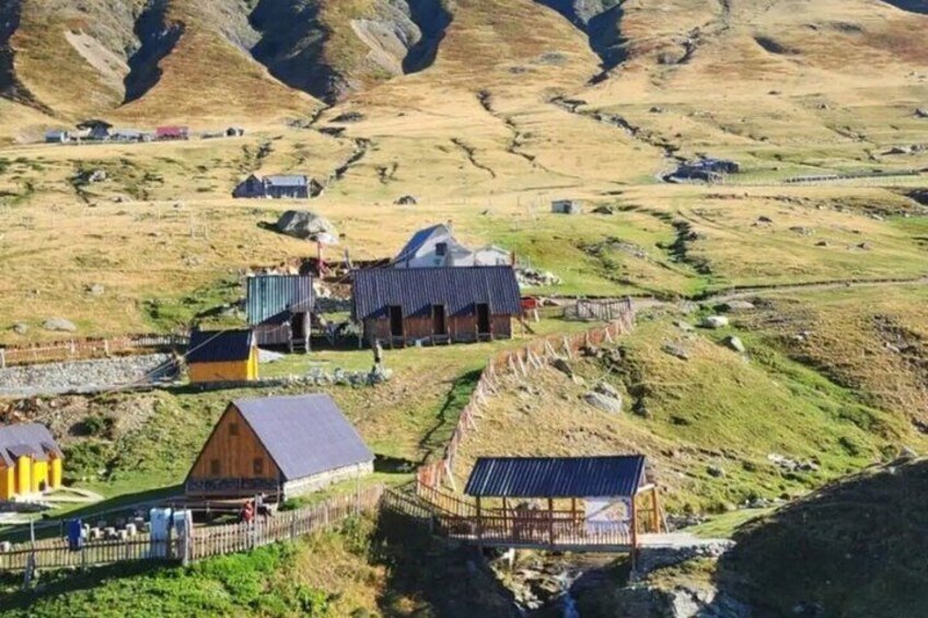 A rural village with houses, a small church, and a mountain backdrop. 2
