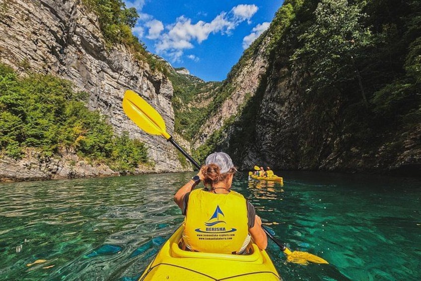 Une personne pratiquant le kayak dans une rivière, entourée de falaises rocheuses et de verdure. 1