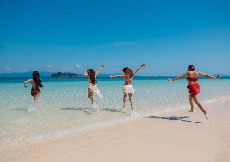 Four people running on a sandy beach with clear blue water and a distant island. 5