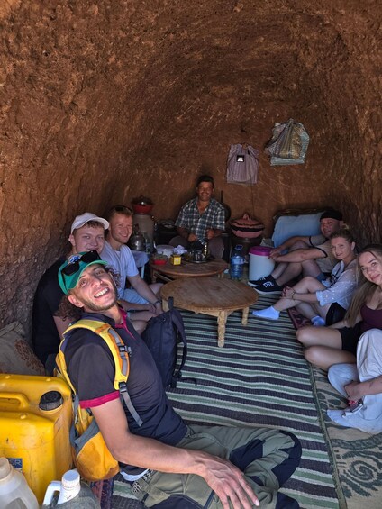 A group of people inside a cave with a wooden table and chairs. 3