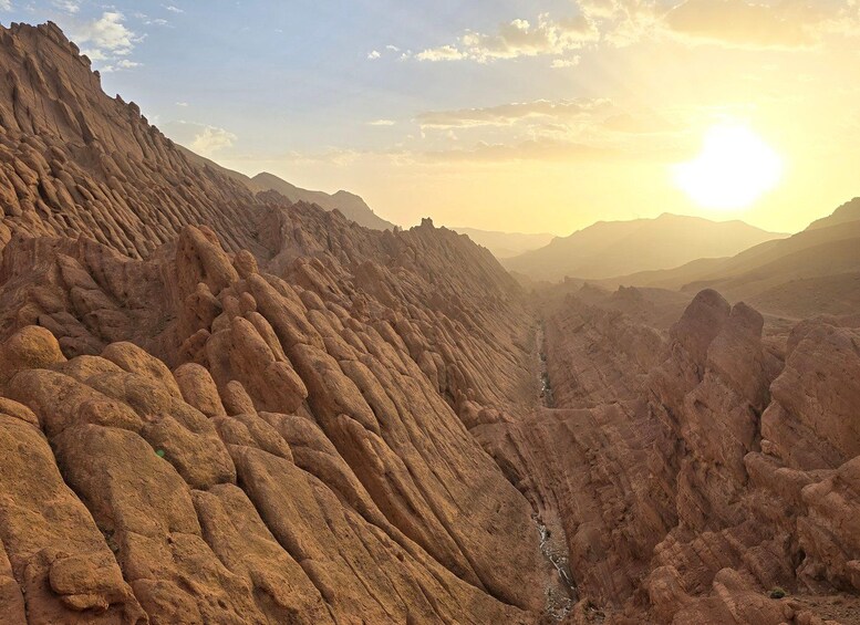 A rugged canyon landscape with layered rock formations and a narrow water channel. 4