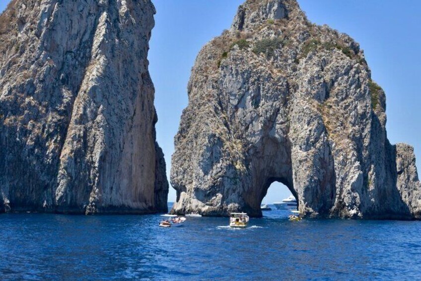 A rocky arch formation with boats in the water. 1