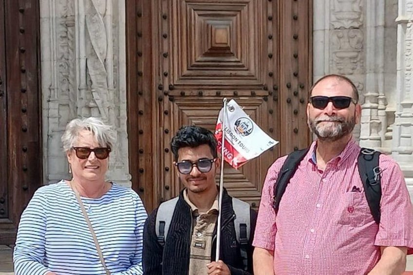 Tres personas de pie frente a una puerta de madera grande con tallas elaboradas. 4