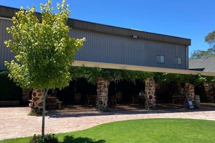 A building with a covered patio area, stone pillars, and a tree. 2