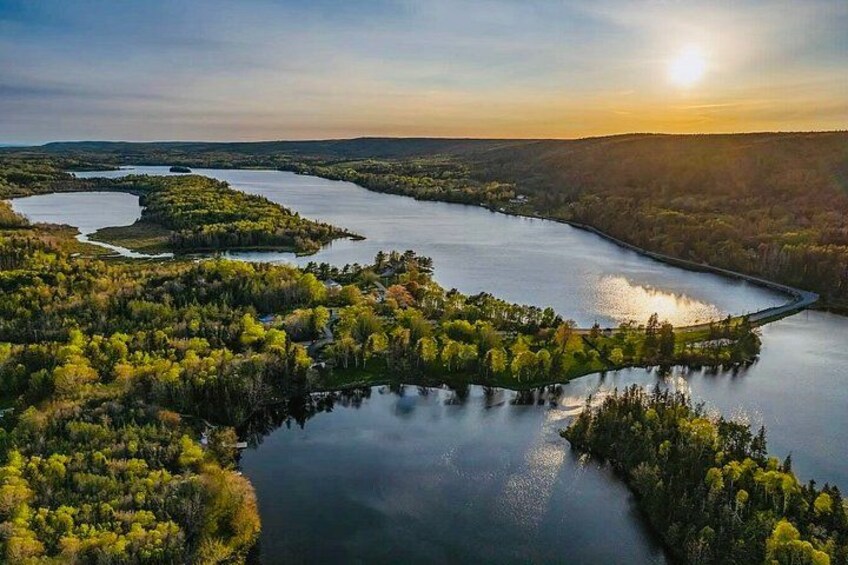 A river winding through a forested landscape with a sunrise in the background. 1