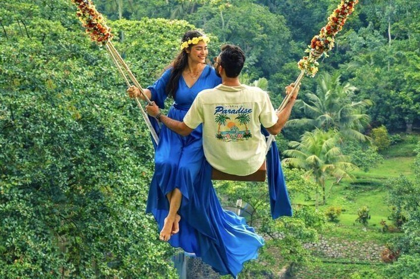 Un couple est assis sur une balançoire, avec en arrière-plan un paysage verdoyant et luxuriant. 4