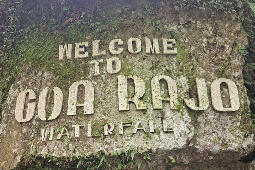Un rocher recouvert de mousse sur lequel on peut lire les inscriptions suivantes : « BIENVENUE À GOA RAJO » et « PAS D’EAU ». 5
