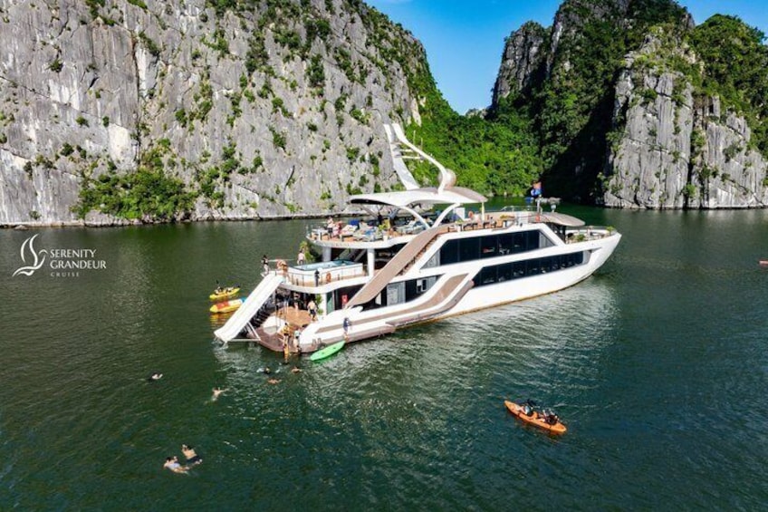A large white yacht docked near rocky cliffs with a small boat nearby. 5