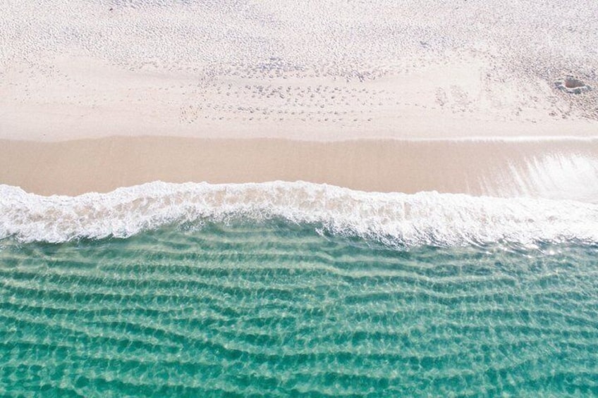 Een strand met helder turquoise water en een zandkust. 1