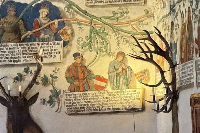 A historical mural with figures, text, and a deer head. 3