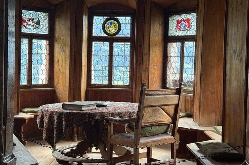 A wooden interior with a table, chairs, and stained glass windows. 4