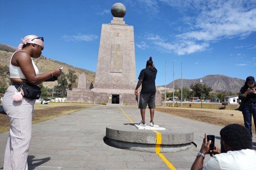 Un monumento con una parte superior esférica, una persona de pie frente a él, y otra persona tomando una fotografía. 3