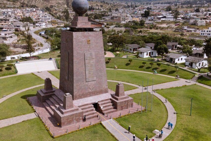 Un gran monumento con una parte superior esférica, rodeado de un césped cuidado y algunas personas caminando. 5