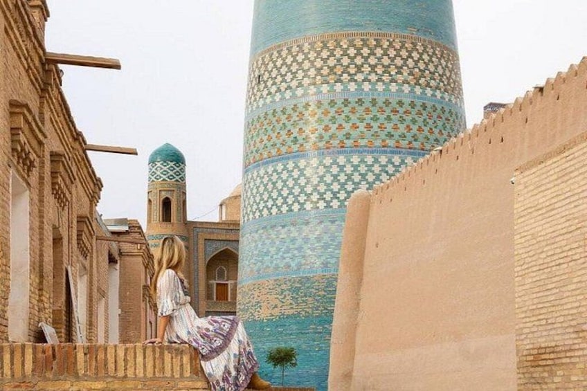 A historic building with a patterned tower, a small tree, and a person in traditional attire. 3