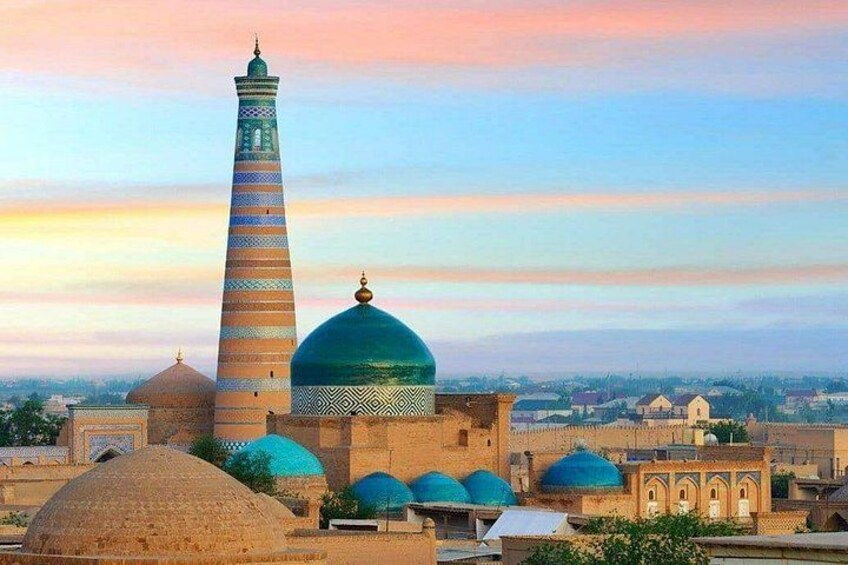 A mosque with a tall minaret and domes, set against a sunset sky. 5