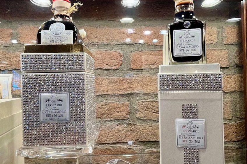 Two bottles of Balsamoro liquor on display against a brick wall. 5