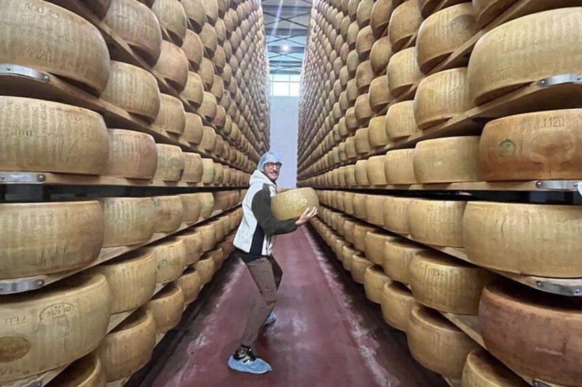 A person in a warehouse holding a large wooden barrel. 3
