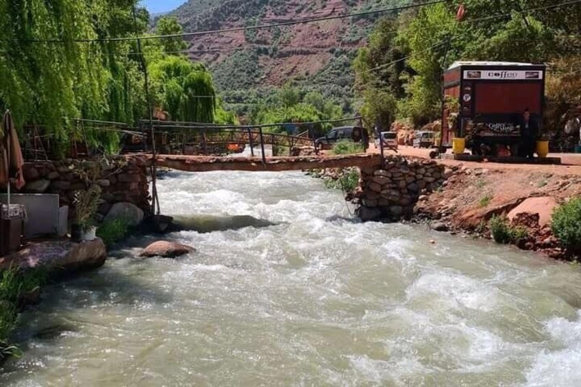 Une rivière traversée par un pont, un véhicule rouge et un paysage montagneux en arrière-plan. 2