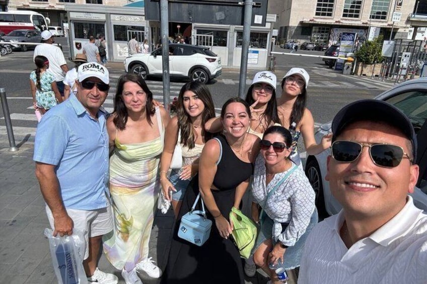 A group of people posing on a city sidewalk with buildings and cars in the background. 4
