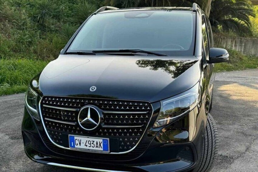 A black Mercedes SUV parked on a road with greenery in the background. 5