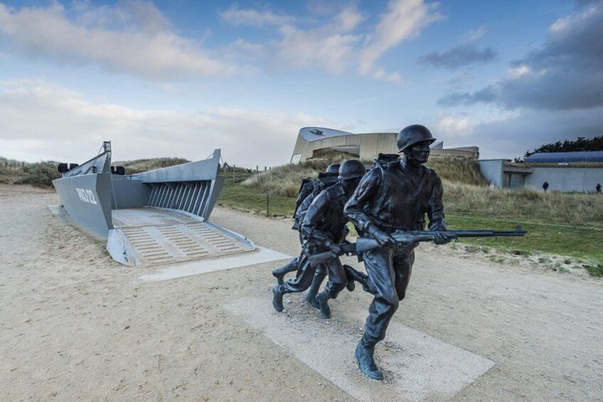 A beach with a large boat sculpture, a concrete ramp, and a building in the background. 3